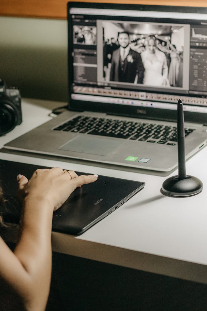 Woman using a graphics tablet to edit wedding photos on a laptop.